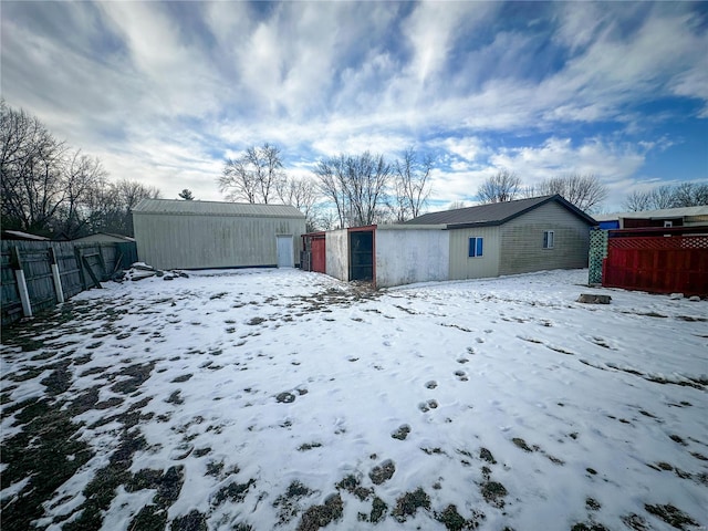 snow covered back of property featuring an outdoor structure