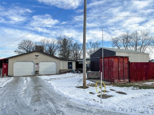 view of snowy exterior featuring a garage and an outbuilding