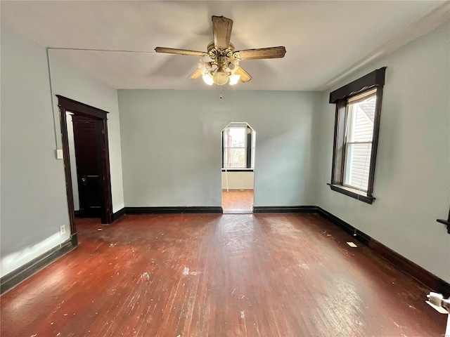 empty room featuring plenty of natural light, dark hardwood / wood-style floors, and ceiling fan