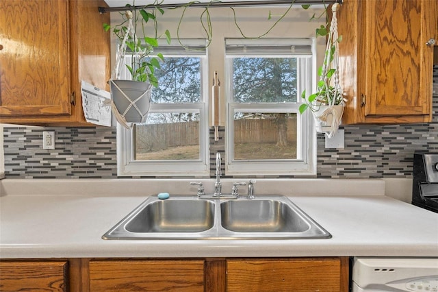 kitchen featuring washer / clothes dryer, backsplash, a healthy amount of sunlight, and sink