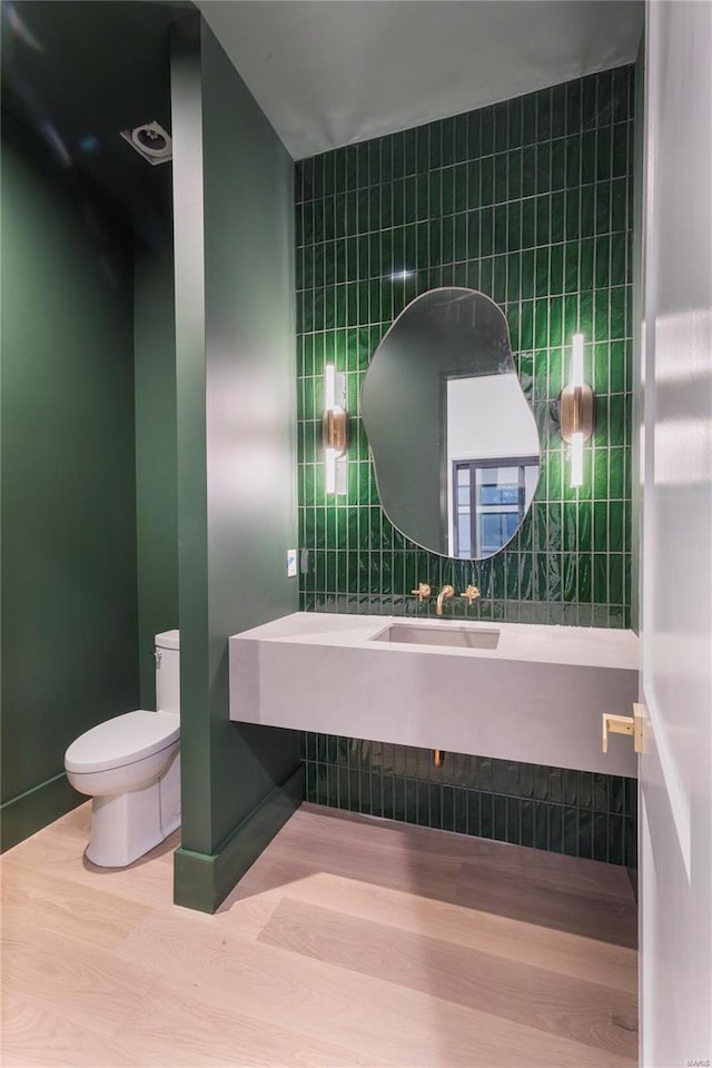 bathroom with tile walls, sink, hardwood / wood-style flooring, and toilet