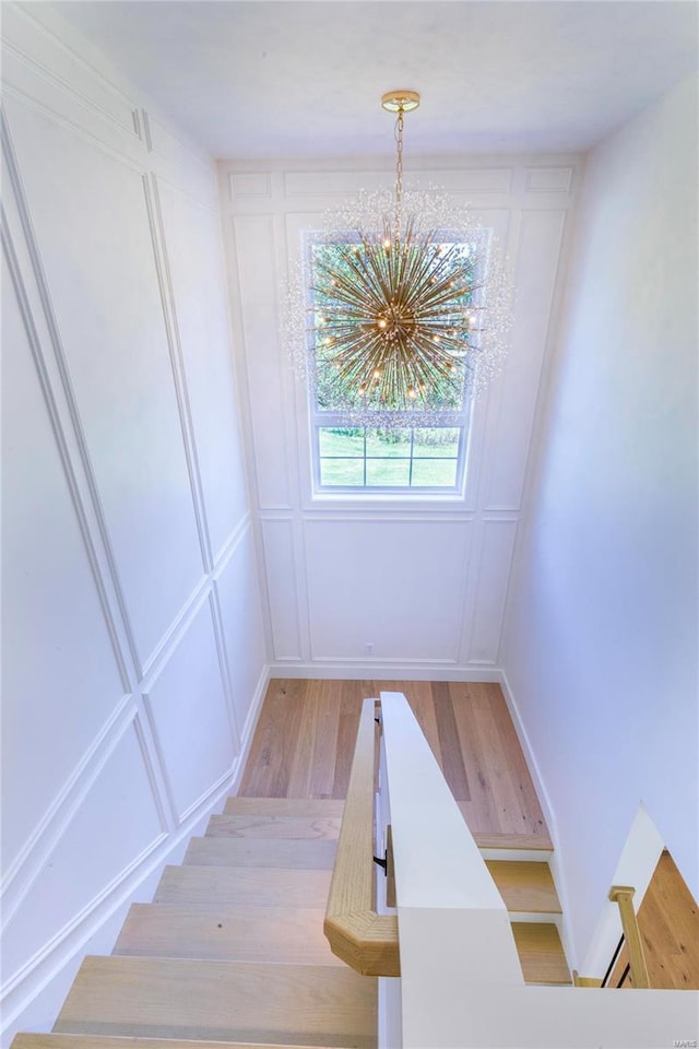 staircase with hardwood / wood-style flooring and a chandelier