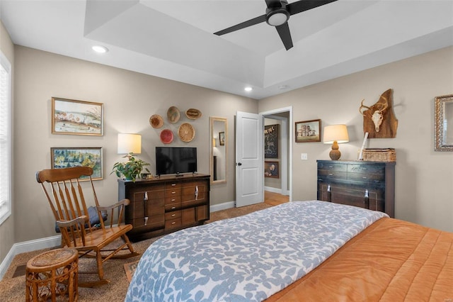 bedroom with ceiling fan, a tray ceiling, and multiple windows