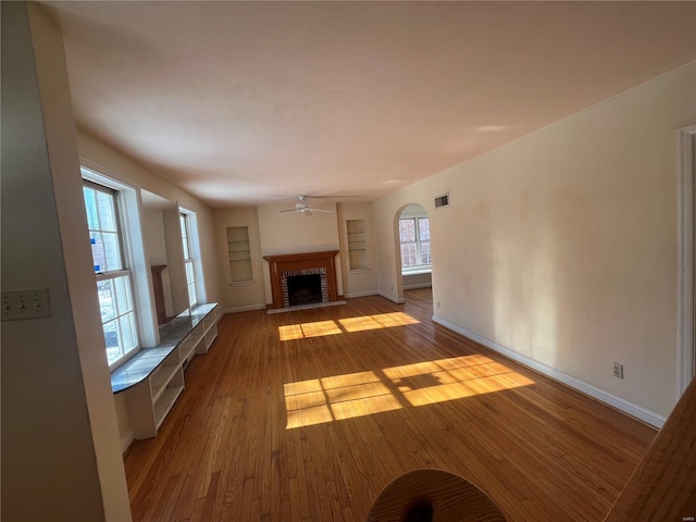 unfurnished living room featuring a brick fireplace, ceiling fan, and light hardwood / wood-style flooring