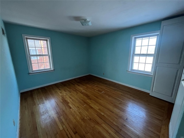 empty room with a healthy amount of sunlight and dark hardwood / wood-style floors