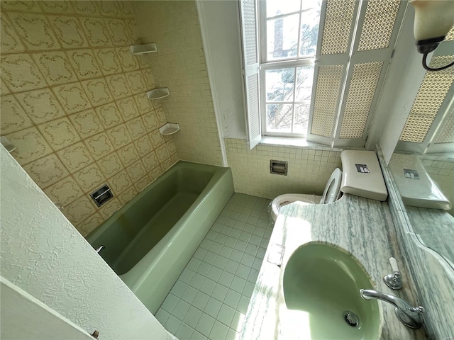 bathroom featuring toilet, sink, tile patterned flooring, and tile walls