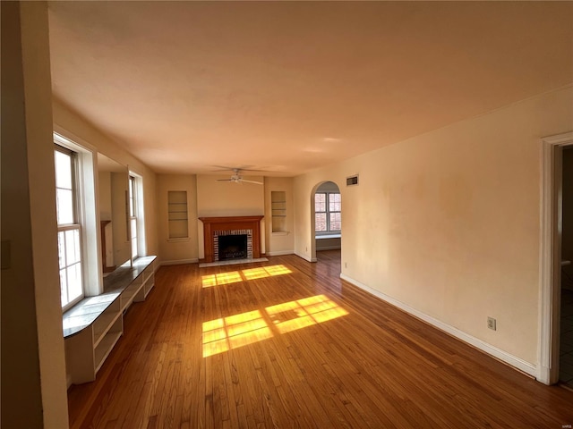 unfurnished living room featuring ceiling fan, hardwood / wood-style floors, and a fireplace