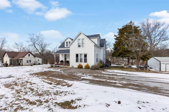 snow covered rear of property featuring covered porch