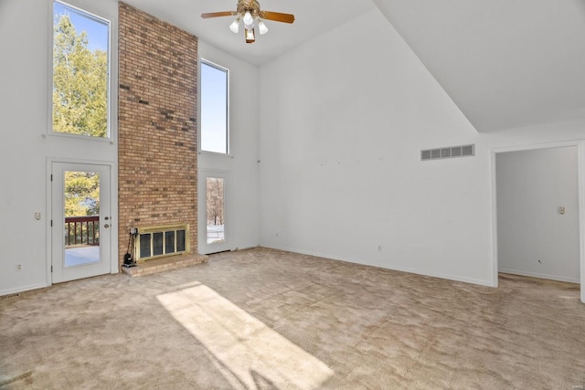 unfurnished living room featuring ceiling fan, a fireplace, light carpet, plenty of natural light, and high vaulted ceiling