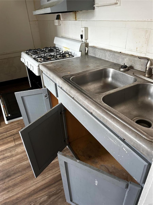 kitchen featuring sink, backsplash, white range with gas stovetop, exhaust hood, and dark wood-type flooring