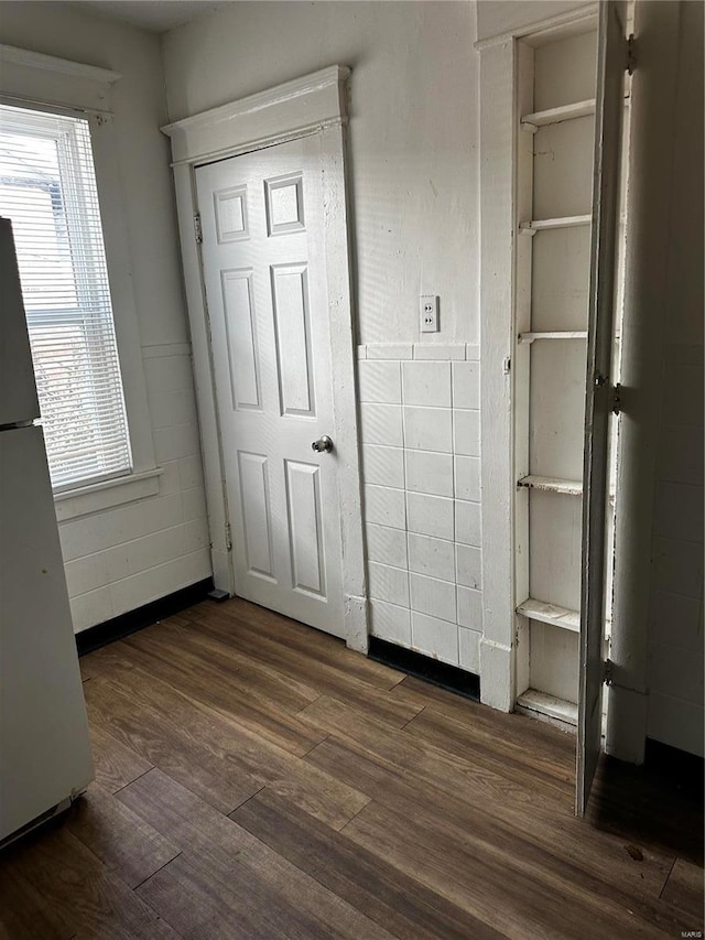 unfurnished bedroom featuring white fridge and dark hardwood / wood-style flooring