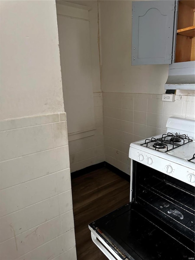 kitchen with tile walls, dark wood-type flooring, gray cabinets, and white gas range