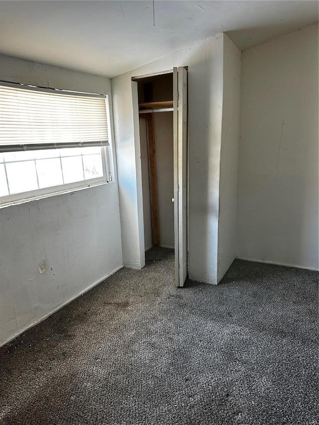 unfurnished bedroom featuring a closet and dark carpet