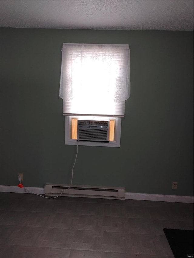 empty room featuring a textured ceiling, cooling unit, and baseboard heating