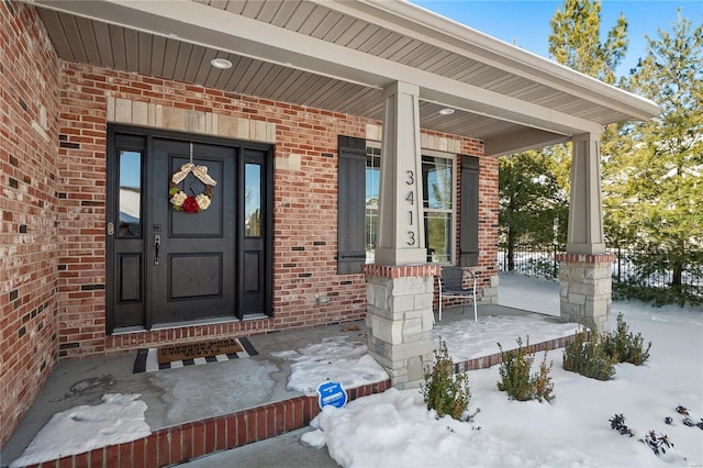 snow covered property entrance featuring covered porch