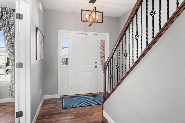 foyer entrance with an inviting chandelier and dark wood-type flooring