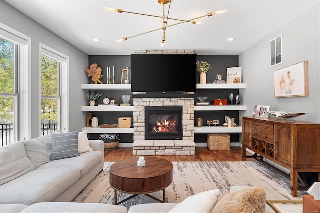 living room featuring a fireplace, wood-type flooring, and a notable chandelier