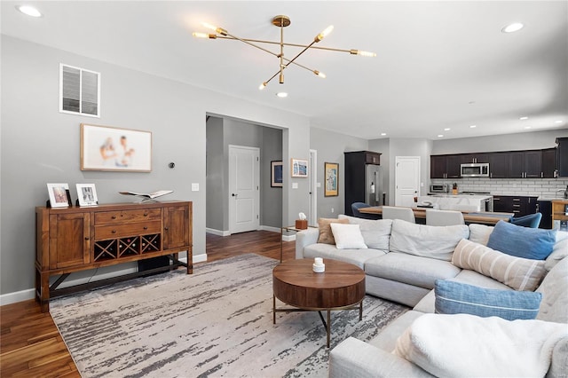 living room featuring wood-type flooring and an inviting chandelier