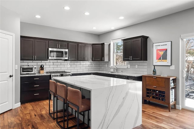 kitchen with a kitchen breakfast bar, tasteful backsplash, sink, hardwood / wood-style flooring, and a center island