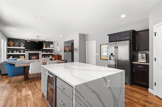 kitchen with light stone countertops, a center island, beverage cooler, high quality fridge, and a fireplace