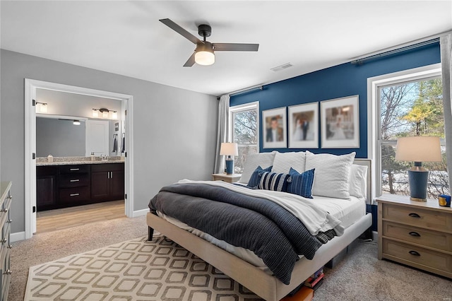 bedroom with light carpet, ensuite bath, ceiling fan, and sink