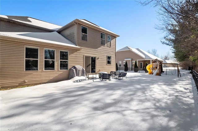 snow covered rear of property featuring a playground