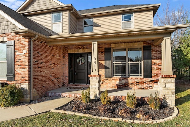 view of exterior entry featuring brick siding and a porch