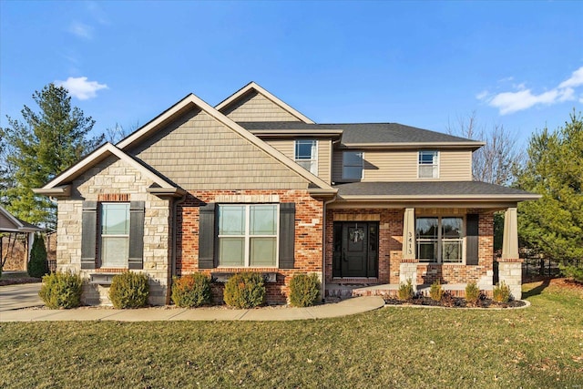 craftsman house with brick siding, stone siding, covered porch, and a front lawn