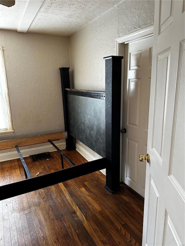 unfurnished bedroom with a textured ceiling and dark hardwood / wood-style flooring