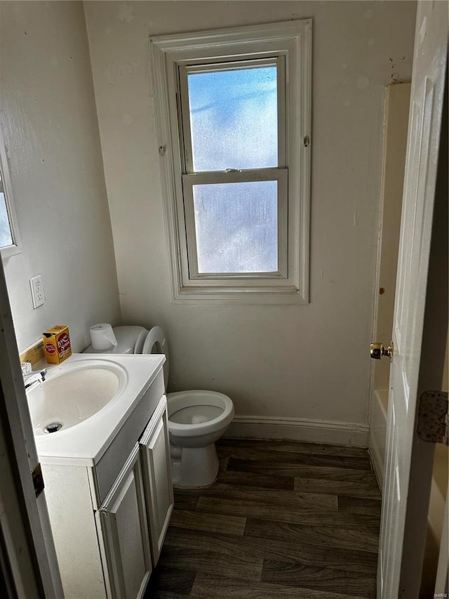 bathroom featuring a tub, hardwood / wood-style floors, toilet, and vanity