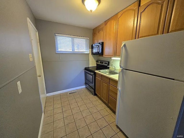 kitchen featuring stainless steel range with electric cooktop, white refrigerator, sink, decorative backsplash, and light tile patterned floors