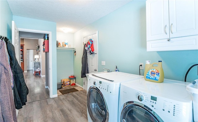 clothes washing area with independent washer and dryer, a textured ceiling, hardwood / wood-style floors, cabinets, and sink