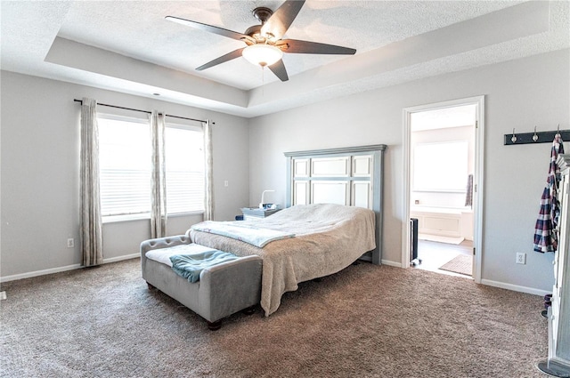 carpeted bedroom featuring a textured ceiling, ceiling fan, a tray ceiling, and connected bathroom