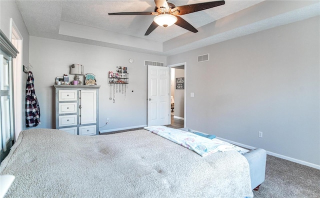 bedroom with ceiling fan, carpet, a textured ceiling, and a tray ceiling