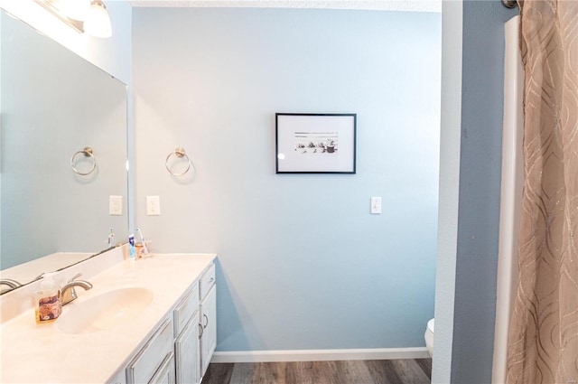 bathroom featuring toilet, wood-type flooring, and vanity