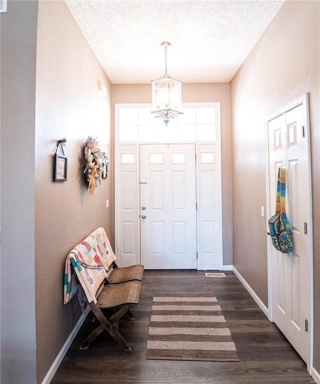 foyer featuring a textured ceiling, a notable chandelier, and dark hardwood / wood-style floors