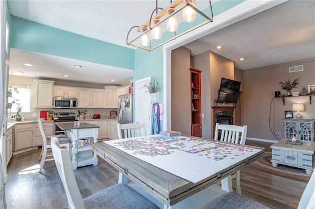 dining area with hardwood / wood-style flooring, an inviting chandelier, a textured ceiling, and a fireplace