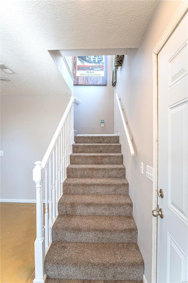 staircase with a textured ceiling