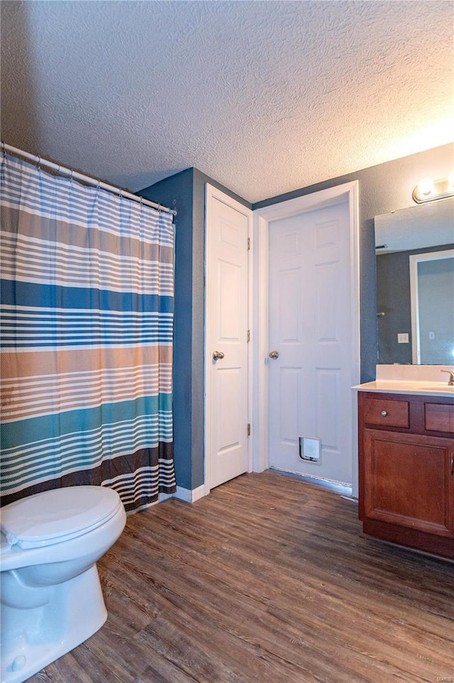 bathroom featuring toilet, hardwood / wood-style flooring, a textured ceiling, and vanity