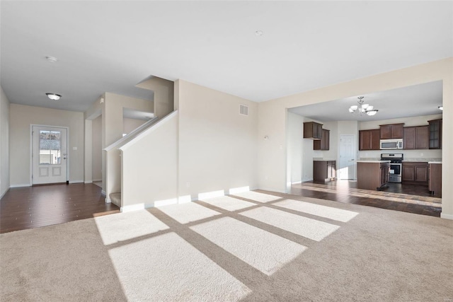 unfurnished living room featuring dark colored carpet and a notable chandelier