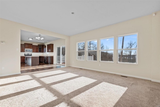 unfurnished living room with light colored carpet and a notable chandelier