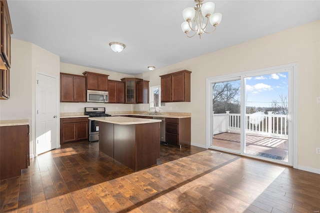 kitchen with sink, a center island, hanging light fixtures, appliances with stainless steel finishes, and dark hardwood / wood-style floors