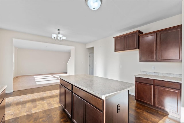 kitchen with dark brown cabinetry, a notable chandelier, dark hardwood / wood-style floors, and a kitchen island