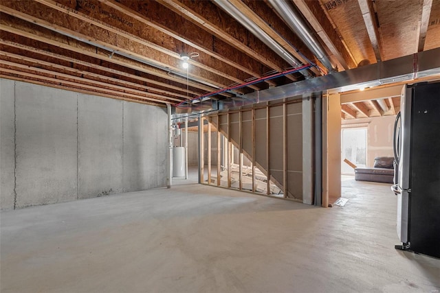 basement with gas water heater and stainless steel fridge