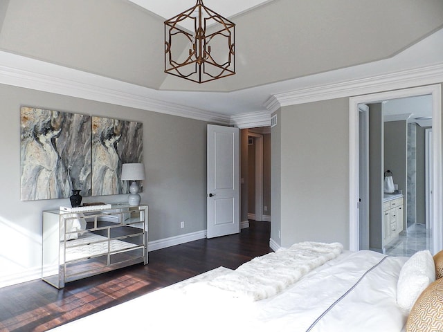 bedroom featuring ensuite bath, dark wood-type flooring, crown molding, a tray ceiling, and a chandelier