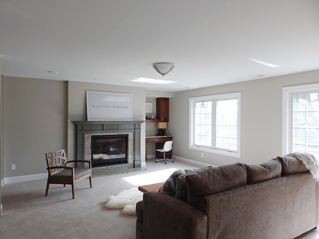 living room featuring plenty of natural light, a premium fireplace, and light carpet