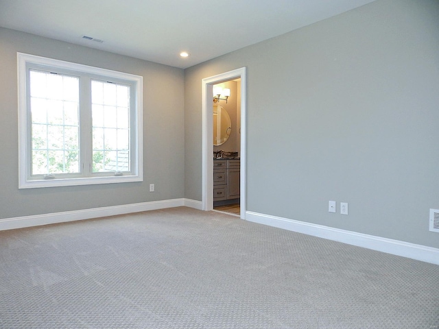 unfurnished bedroom with light carpet, sink, and ensuite bathroom