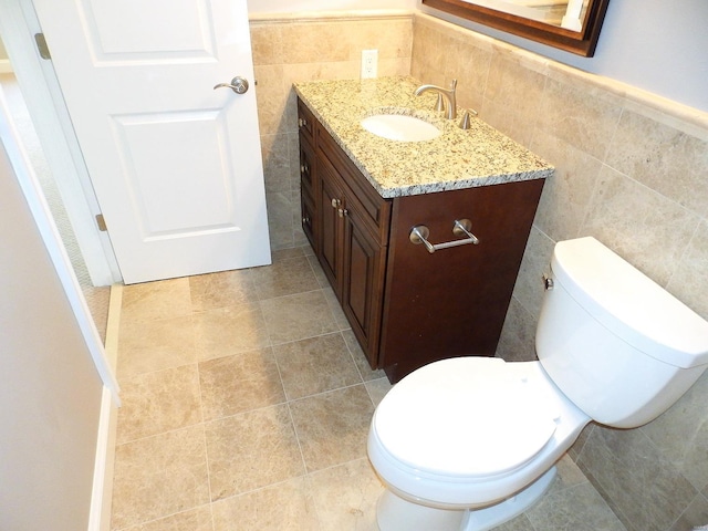 bathroom featuring vanity, toilet, and tile walls