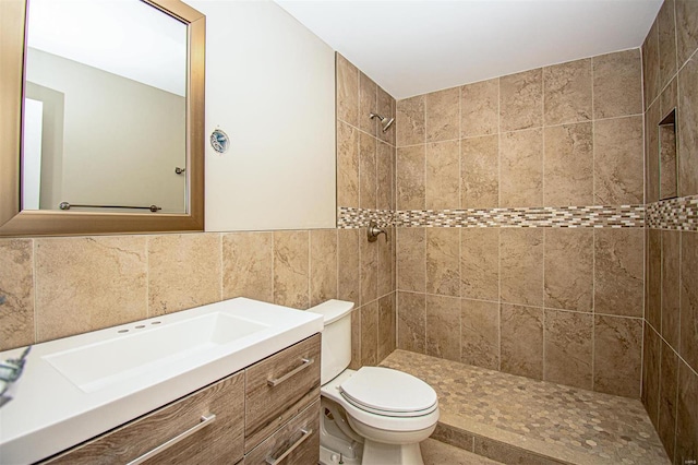 bathroom featuring tile walls, vanity, toilet, and tiled shower