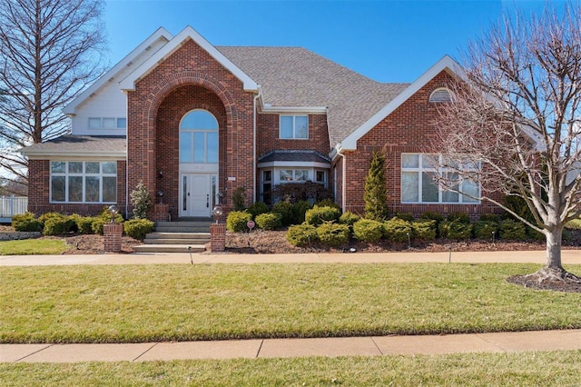 traditional-style house featuring brick siding, roof with shingles, and a front yard